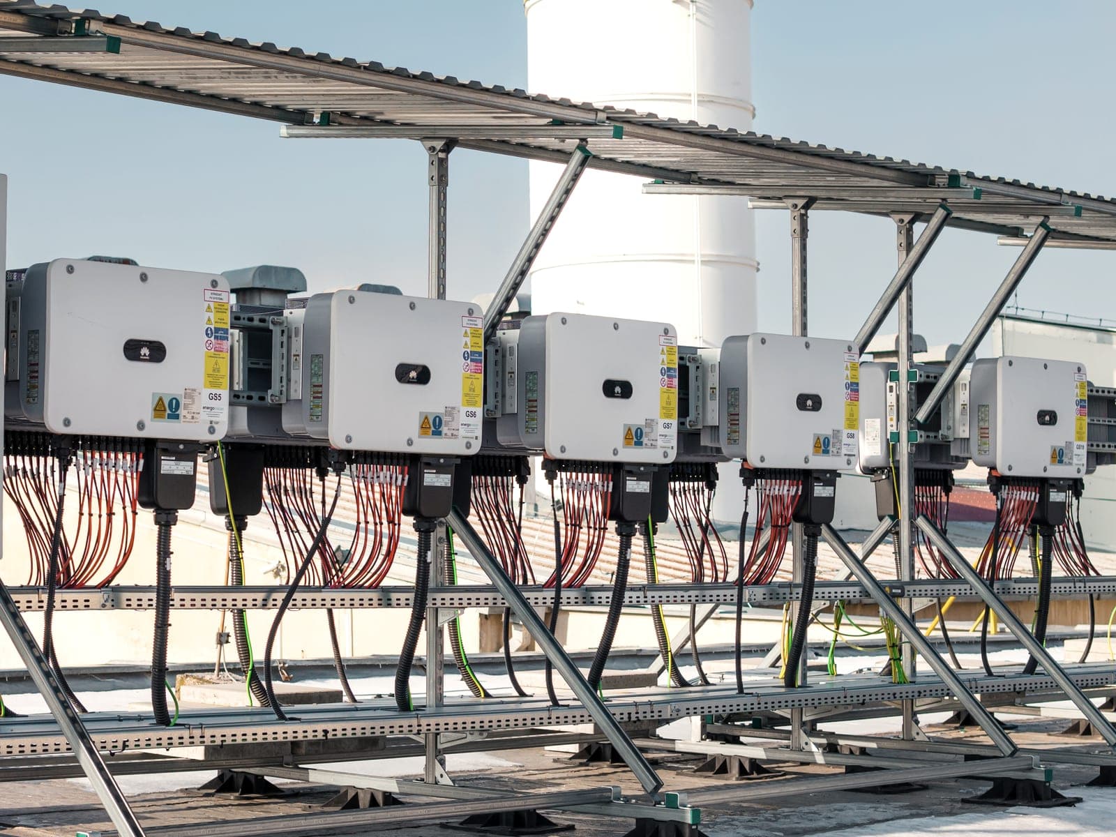 Row of string inverters on a steel structure with red DC cabling